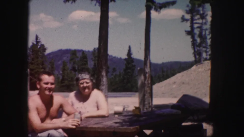 The final frame shows the couple smiling at the table in a Colorado mountain setting, with trees and sky behind them.