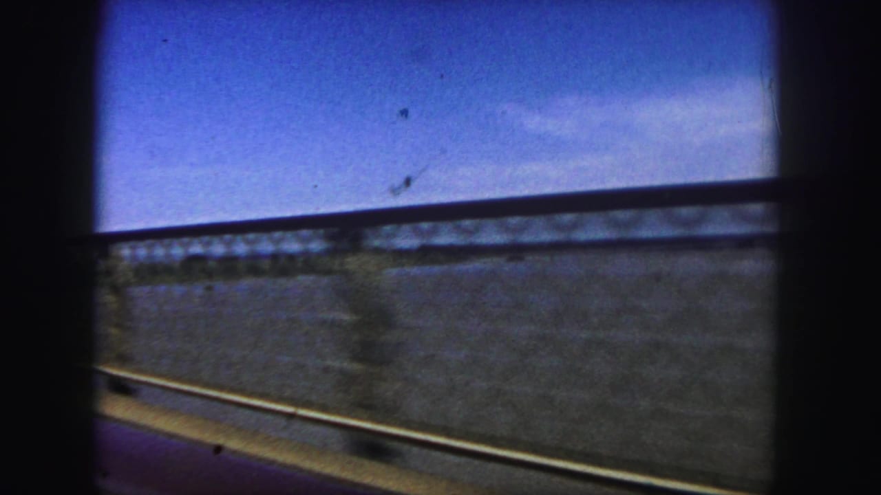 Side view from a moving car showing bridge railing and water below.