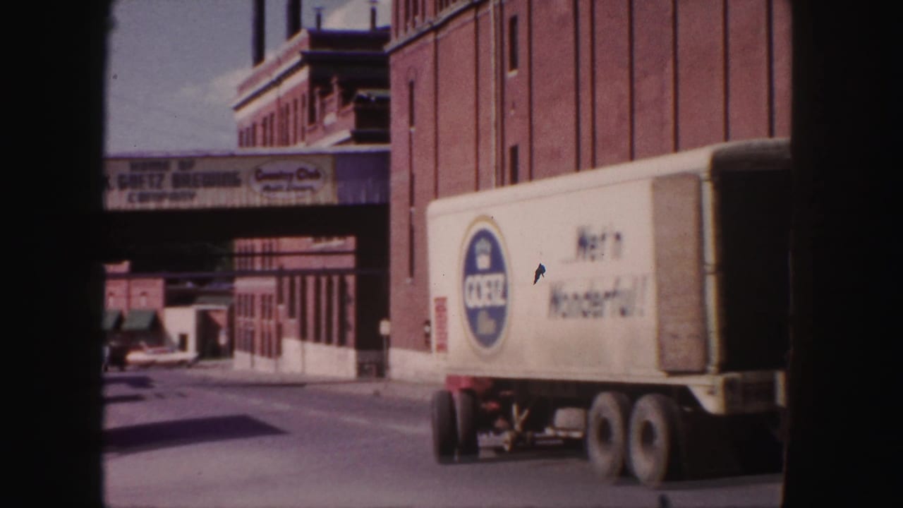 Denver street view showing a box delivery truck beside a brick brewery building with visible Coors and M.K. Grotz signage.