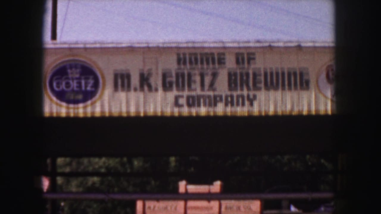 1958 Denver 8mm frame showing the M.K. Goetz Brewing Company sign with a circular Goetz logo on a building facade.