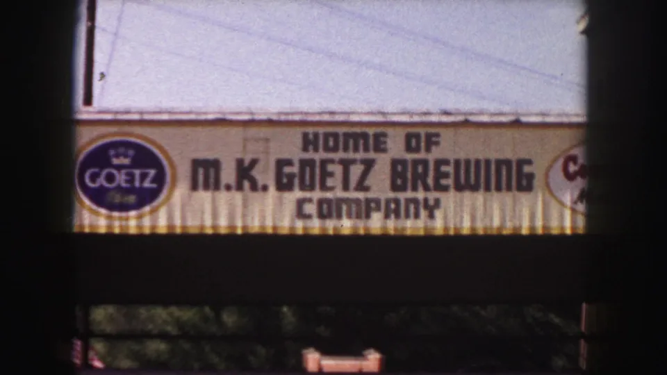 1958 Denver frame showing the brewery sign and Goetz logo on a building facade, with dark foreground framing across the view.