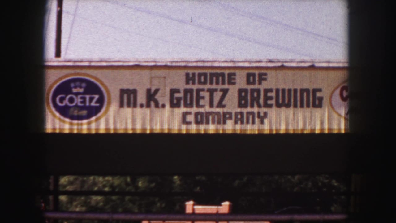 1958 Denver 8mm frame showing the Goetz logo and M.K. Goetz Brewing Company sign cropped by dark film edges.