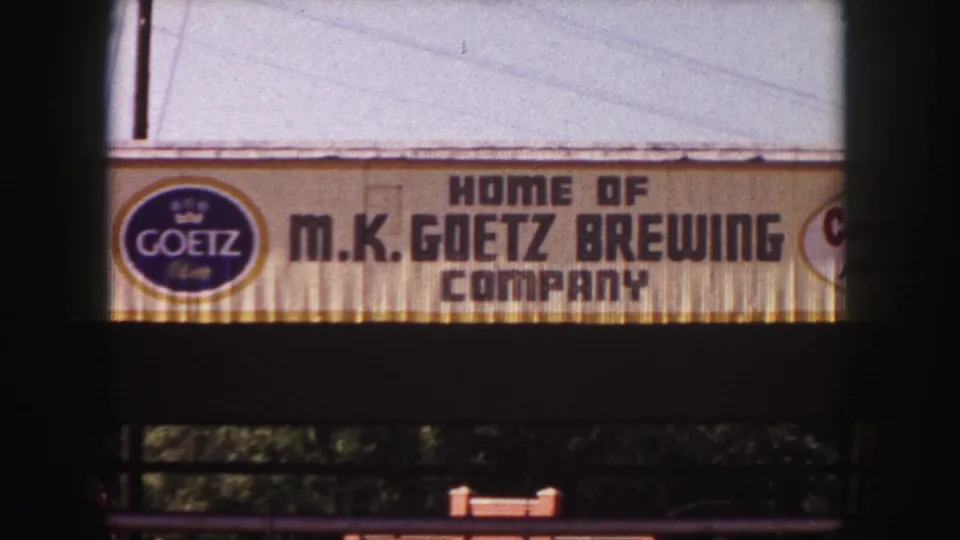 1958 Denver 8mm frame showing the Goetz logo and M.K. Goetz Brewing Company sign cropped by dark film edges.