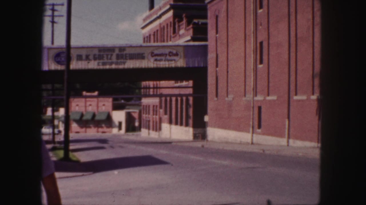 1958 Denver view of the M.K. Goetz Brewing Company bridge with brick buildings and a cropped passerby.
