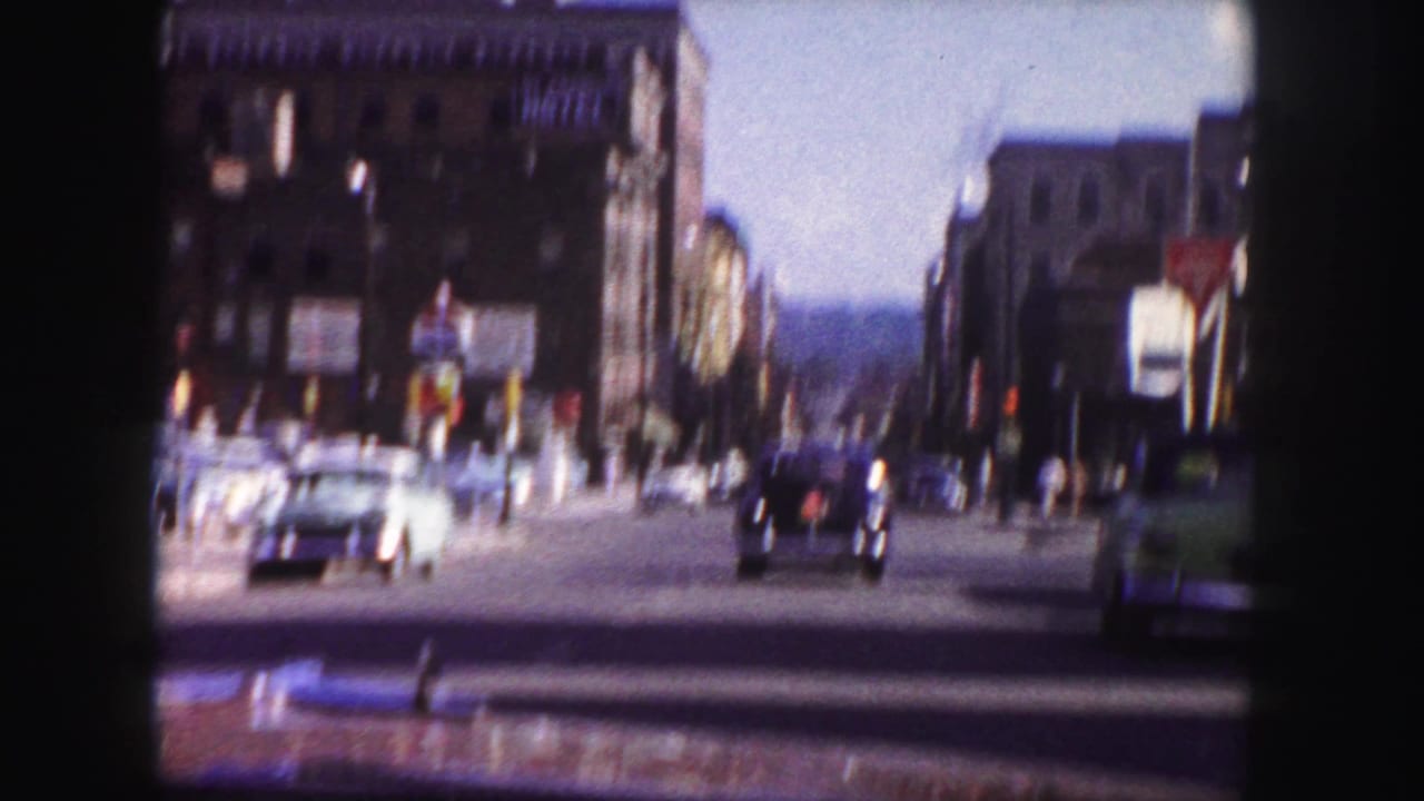 Blurred street view with cars crossing an intersection near tall buildings.