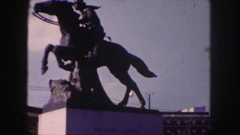 Denver landmark view of the Pony Express statue, showing a rider on a rearing horse silhouetted against a bright sky.
