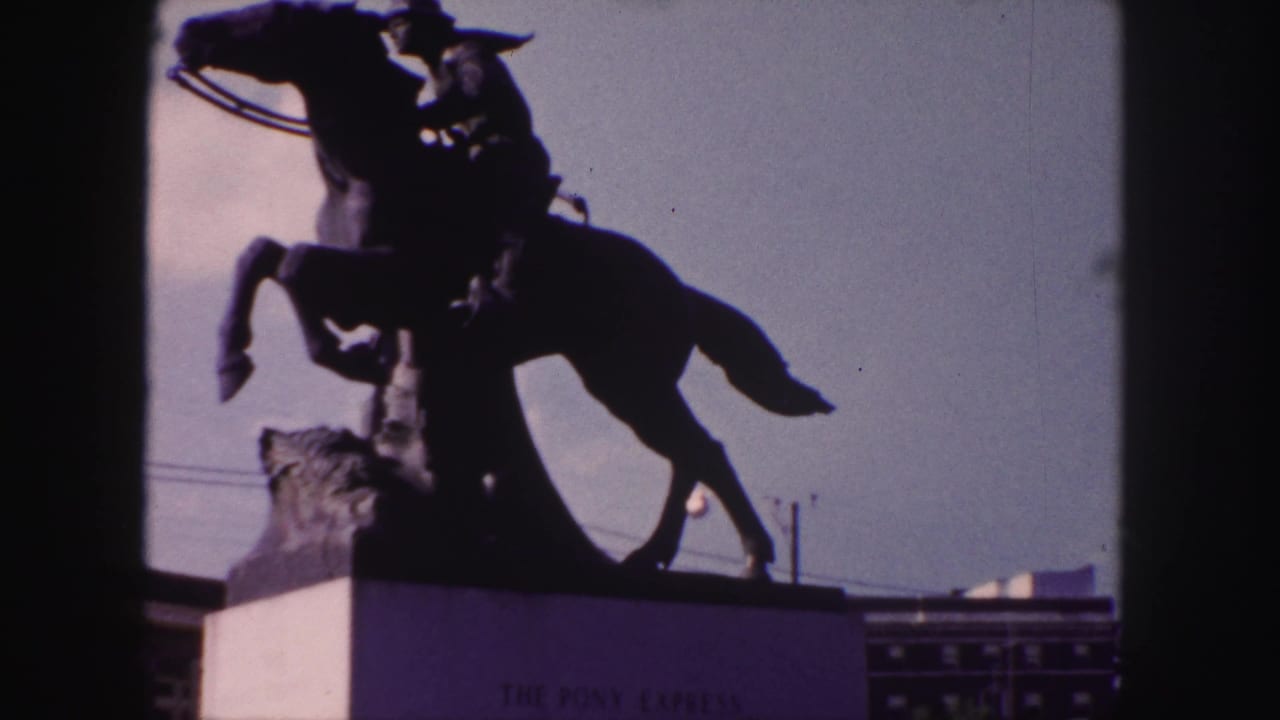 Silhouetted rider on a rearing horse statue above a monument base against a pale sky.