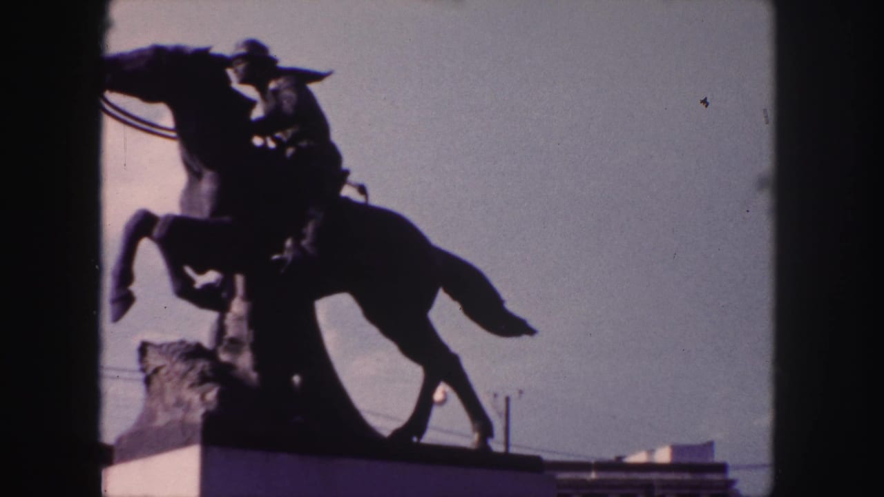 Denver 1958 frame of the horse-and-rider monument, seen in silhouette with roofline and sky behind it.