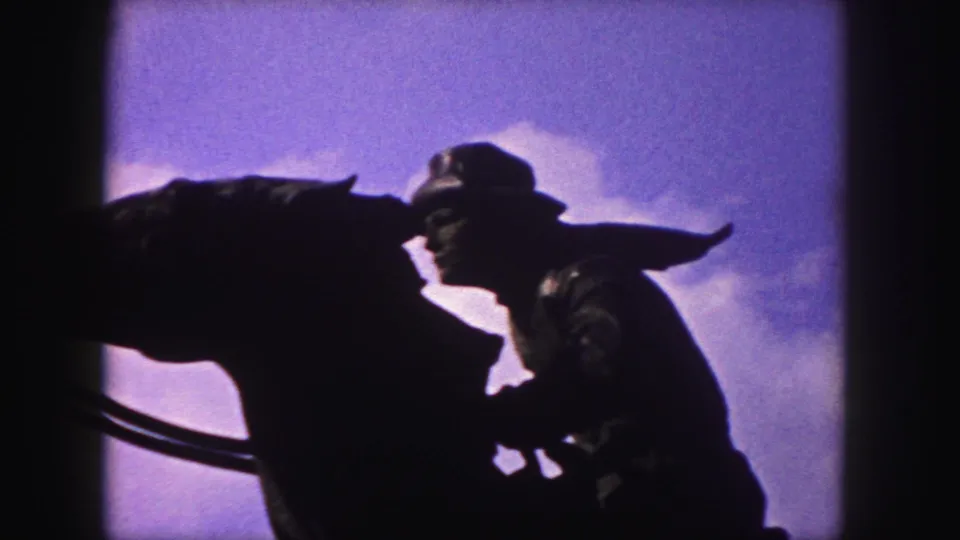 Closer 1958 Denver frame showing the statue rider and horse head in dark silhouette against a blue sky.