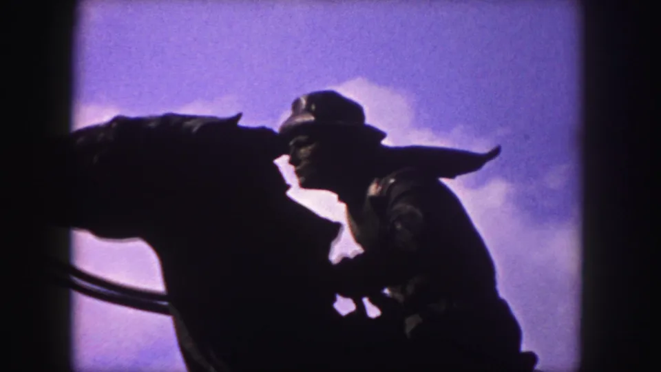 1958 Denver 8mm frame showing a dark mounted cowboy statue in profile against a purple-blue sky and clouds.
