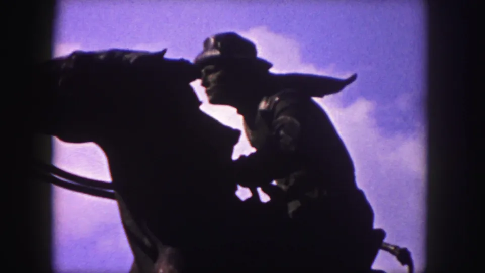 1958 Denver 8mm still with the cowboy rider and horse statue silhouetted, the sky filling most of the background.