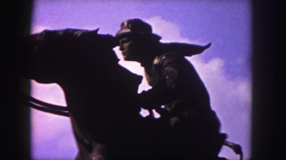Final 1958 Denver frame showing the horse-and-rider statue in silhouette, with clouds and 8mm frame borders visible.