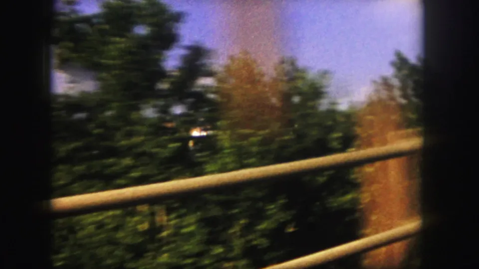 The final 1958 Denver-area frame shows blurred trees, roadside railings, and warm color streaks as the moving car continues past the water view.