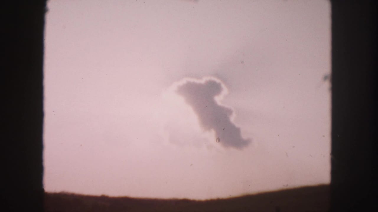 Soft cloud shape over a low dark horizon in a pale sky.