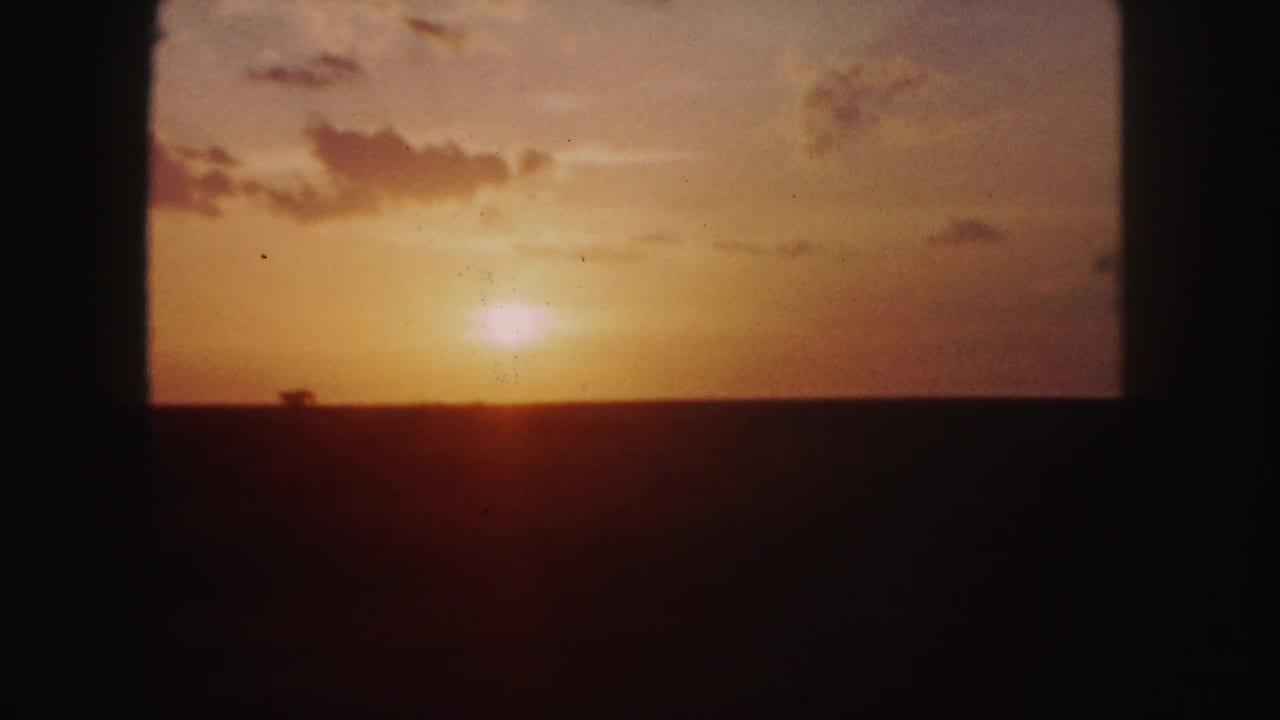 Sunset sky with the sun near the horizon and dark window borders around the view.