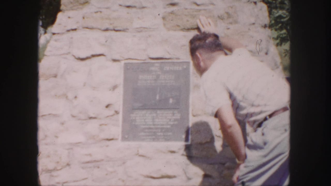 Man remains bent beside the plaque on a stone wall.