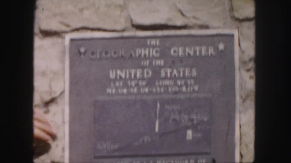 Close 8mm view of the Geographic Center of the United States plaque with coordinates and a small map panel visible.