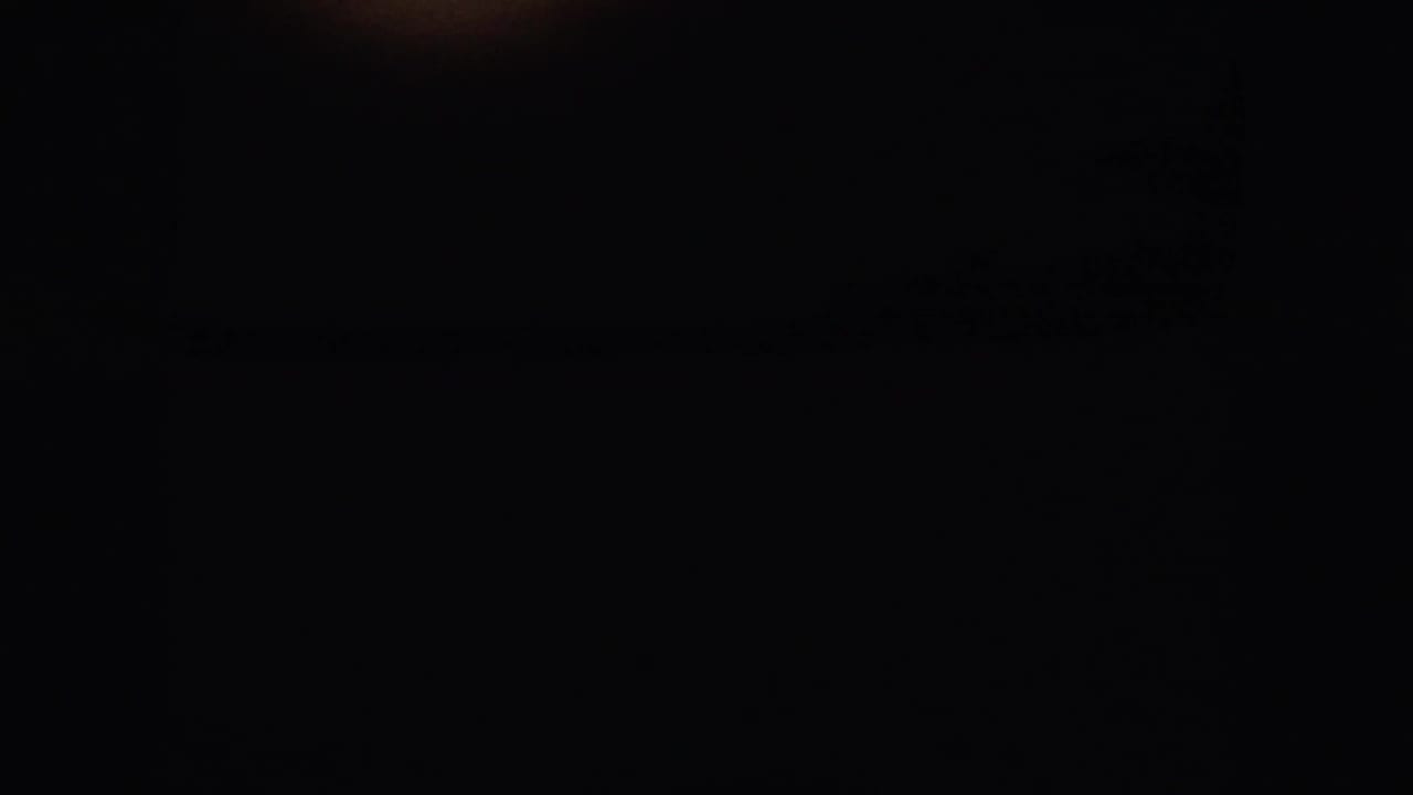 1958 home-movie frame from near Denver showing a dark vehicle-window edge and a distant rural horizon under pale sky.