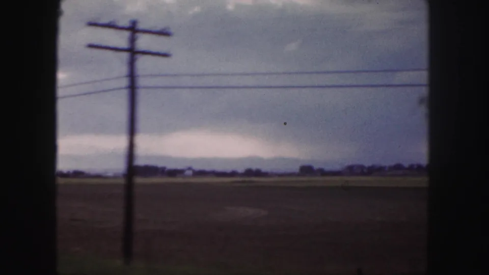 1958 Denver-area travel frame with a roadside utility pole crossing the view over fields and distant horizon.