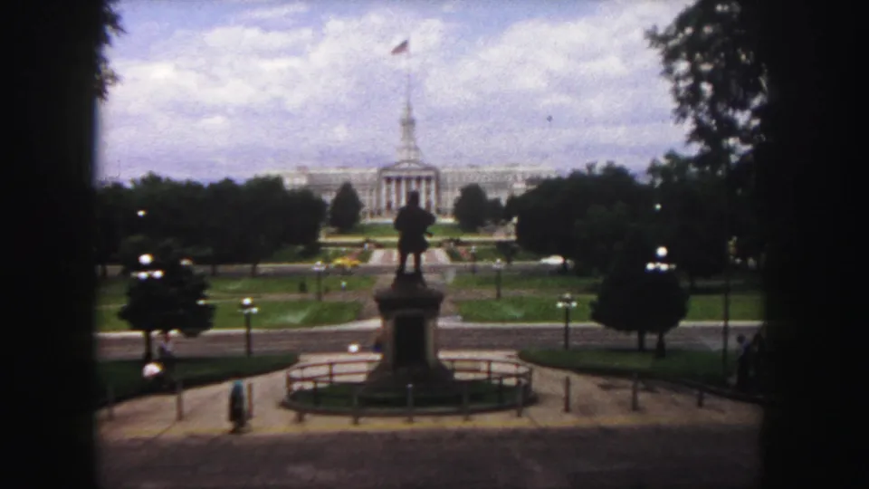 1958 Denver home-movie frame looking across Civic Center Park toward the Colorado State Capitol, with a statue and pathways in front.