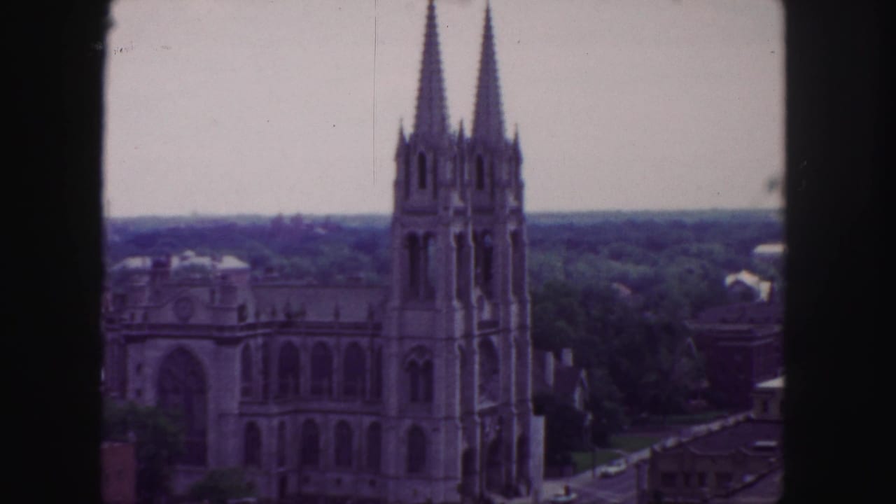 1958 Denver home-movie frame showing a twin-spired church from an elevated vantage point with soft color and visible film borders.