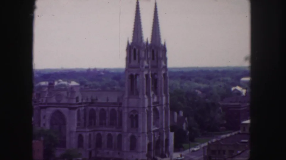1958 Denver home-movie frame showing a twin-spired church from an elevated vantage point with soft color and visible film borders.