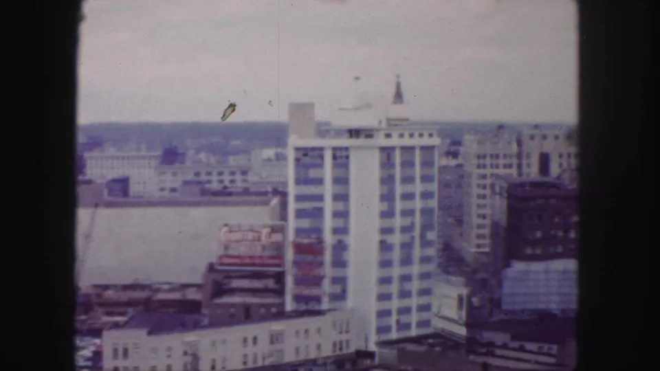Late-1950s Denver skyline frame with a tall modern building, Country Club Beer billboard, construction area, and darker brick building at right.