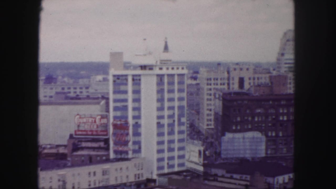 Similar downtown view with the white high-rise centered and a billboard on a lower roof.
