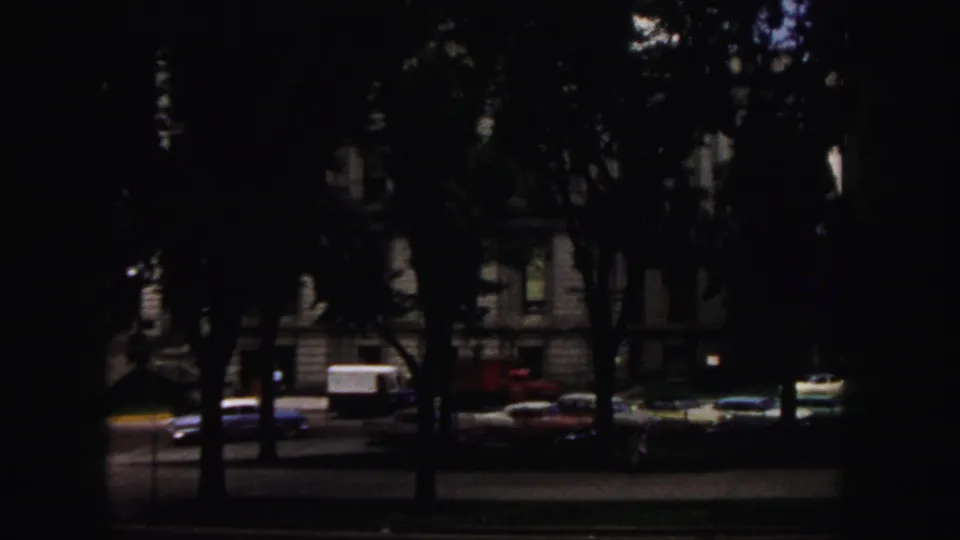 Tree-shaded Denver street scene with parked period cars and a masonry building visible through dark exposure.