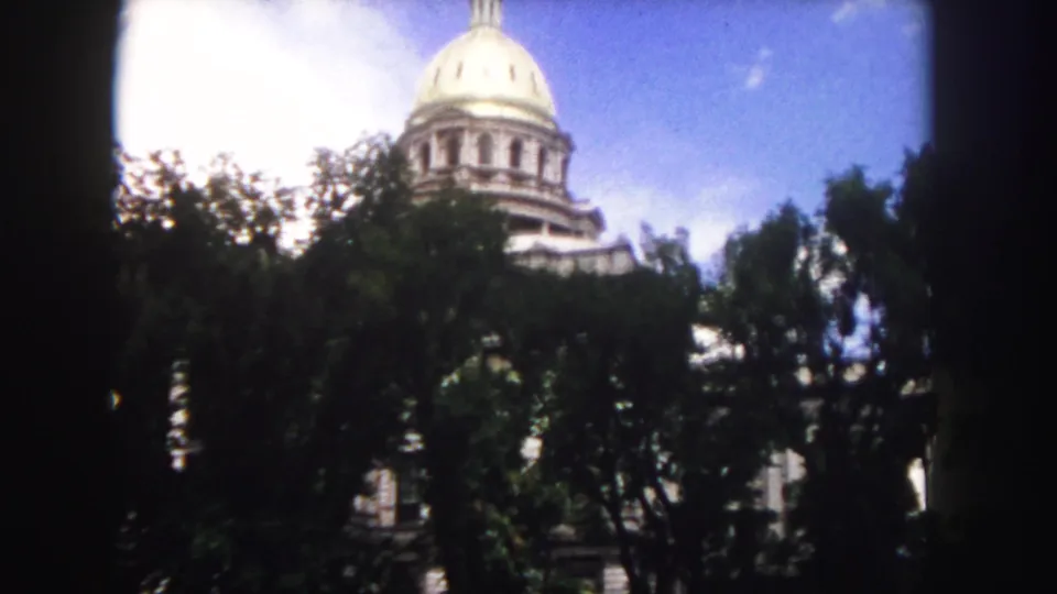 The Colorado State Capitol dome is framed by mature trees in this 1958 Denver 8mm still, with soft focus and strong daylight.