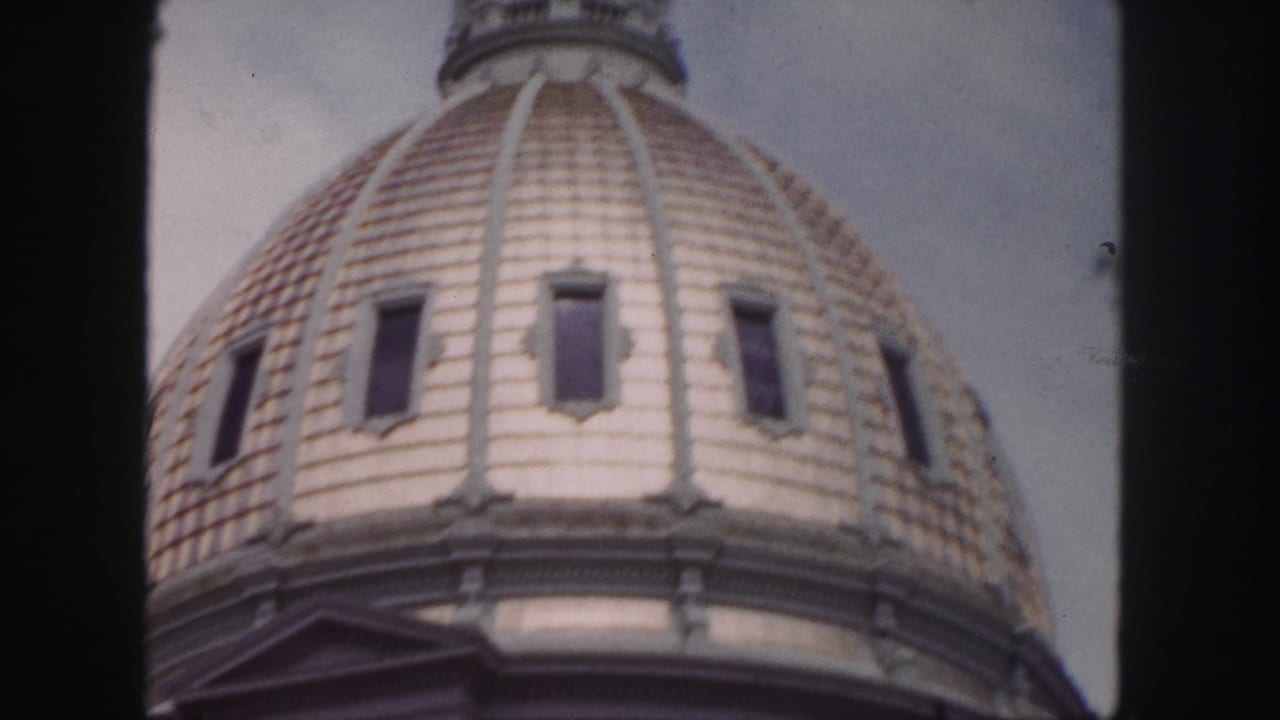 Close view of a domed roof with rectangular windows and ornate trim.