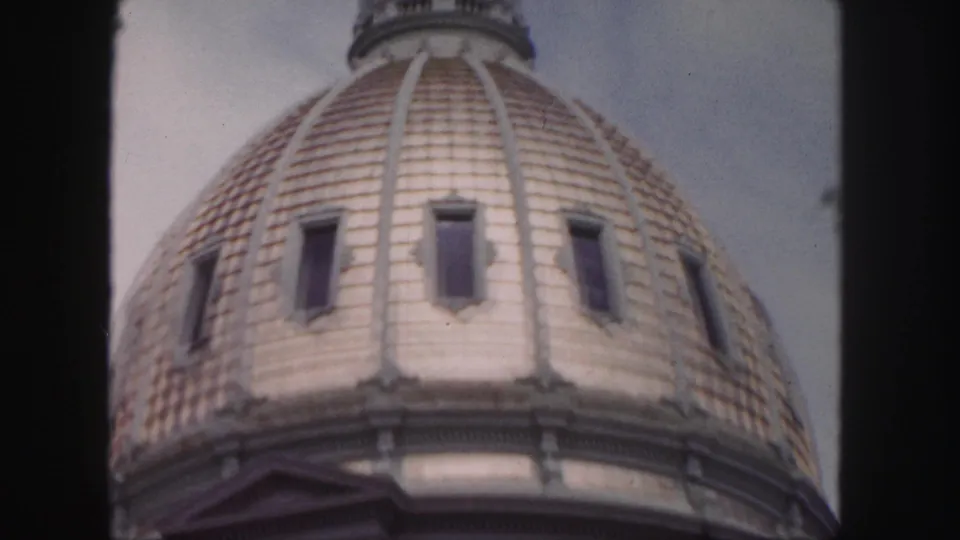 Soft-focused 1958 Denver 8mm frame of the historic dome with roof ribs, rectangular windows, and pale sky.