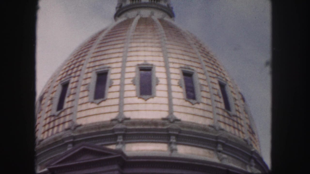 1958 Denver home-movie frame showing a close upward view of a tiled historic building dome with narrow windows.
