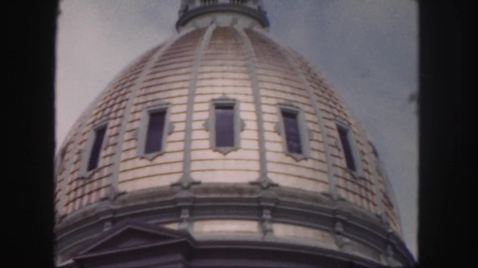 1958 Denver home-movie frame showing a close upward view of a tiled historic building dome with narrow windows.