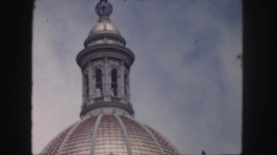 1958 Denver home-movie frame with the dome lantern centered above the curved tiled roof and pale blue sky.