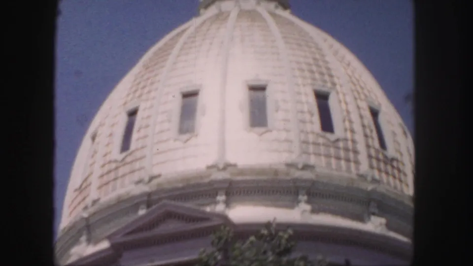 1958 Denver home-movie frame showing the tiled dome surface, narrow windows, and ornamental base trim from below.