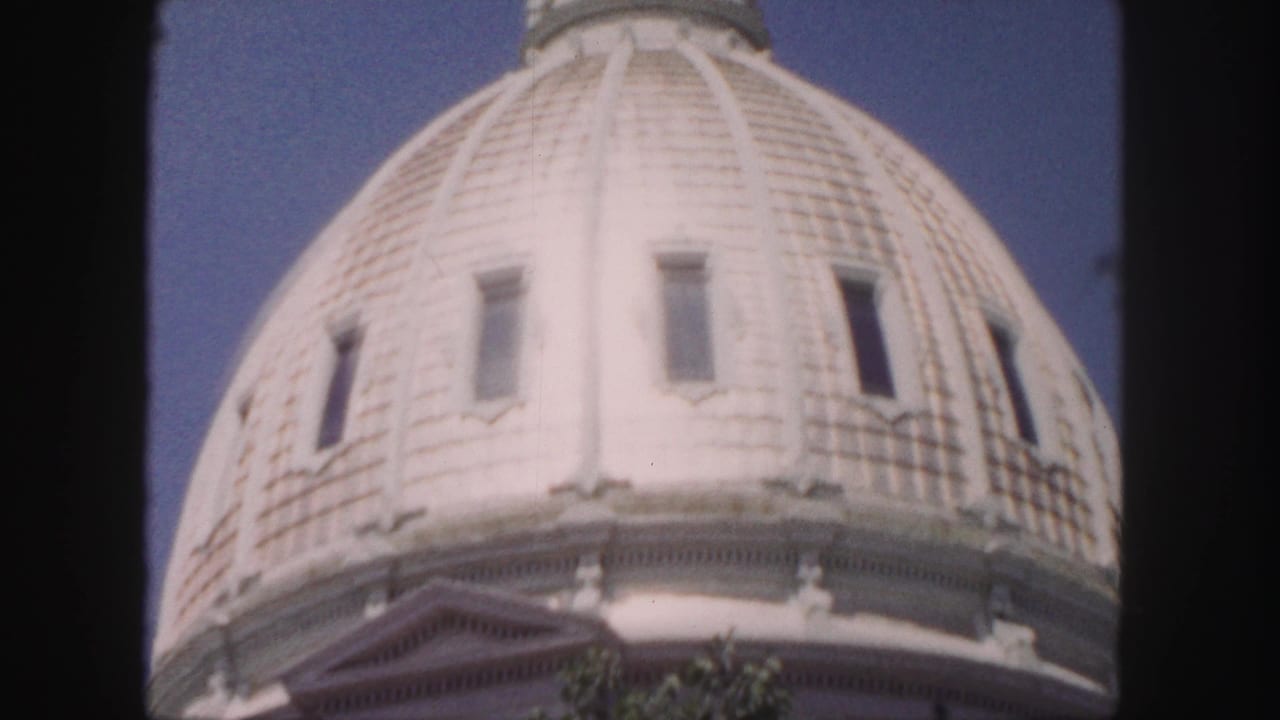 1958 Denver home-movie frame showing a close, soft-focused view of a white segmented dome with narrow windows and ornate trim.