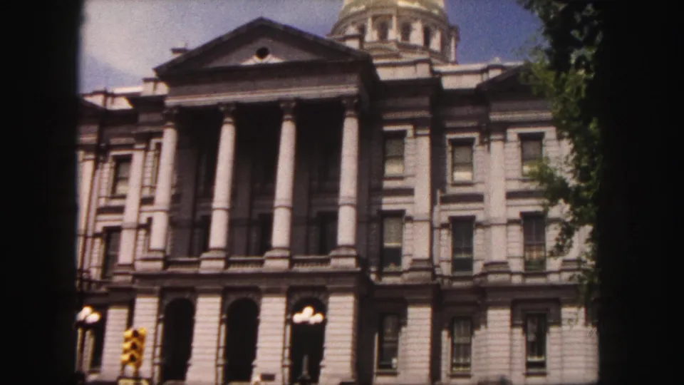 1958 Denver home-movie view of the Colorado State Capitol facade with columns, windows, streetlights, and a traffic signal at the curb.