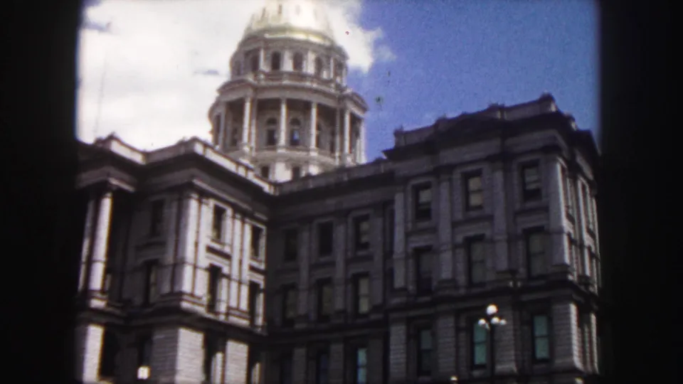 1958 Denver home-movie frame of the Colorado State Capitol, with the dome above the shaded facade and a street lamp near the lower edge.