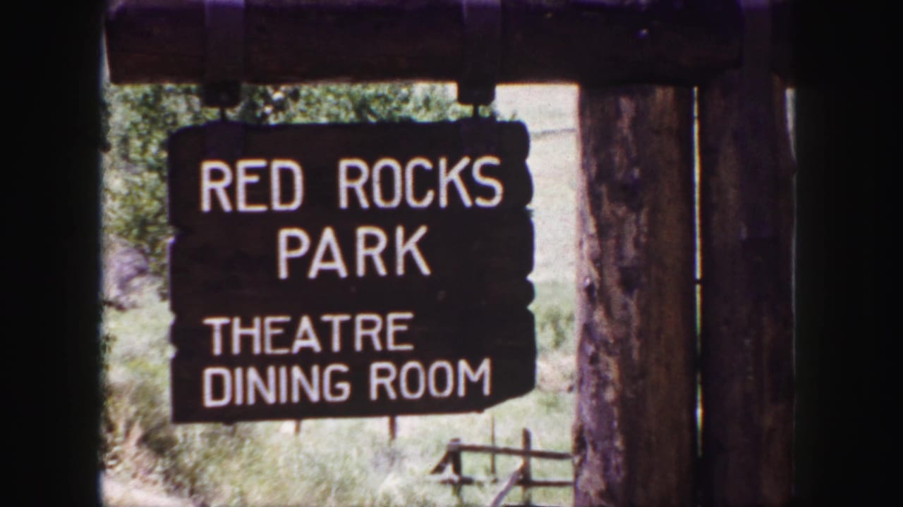 1958 8mm frame of a wooden Red Rocks Park sign reading Theatre and Dining Room beside rough timber posts.