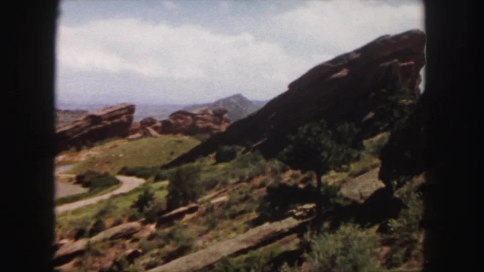 1958 Denver-area scenic frame with sandstone outcrops, hillside greenery, a winding path, distant ridgeline, soft grain, and gate borders.