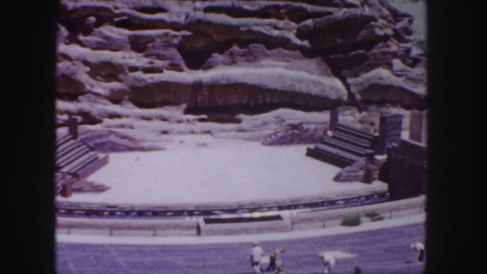 Red Rocks Amphitheatre appears from a visitor's elevated viewpoint, with the stage, cliff face, and distant people visible in 1958 footage.