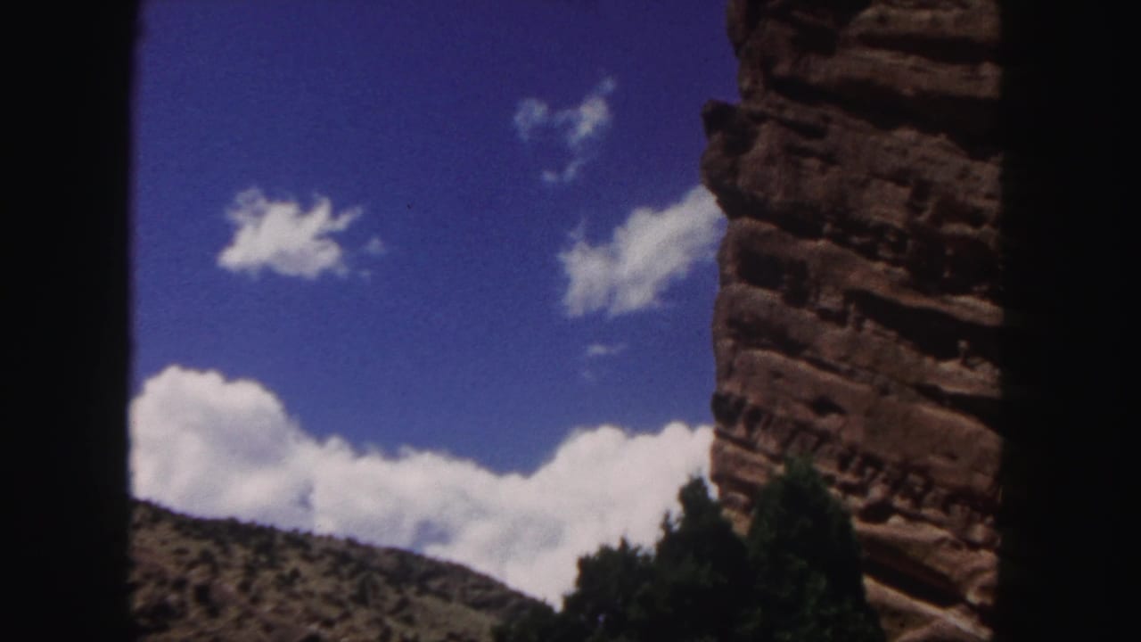 Red rock wall and blue sky framed by dark vertical foreground edges.