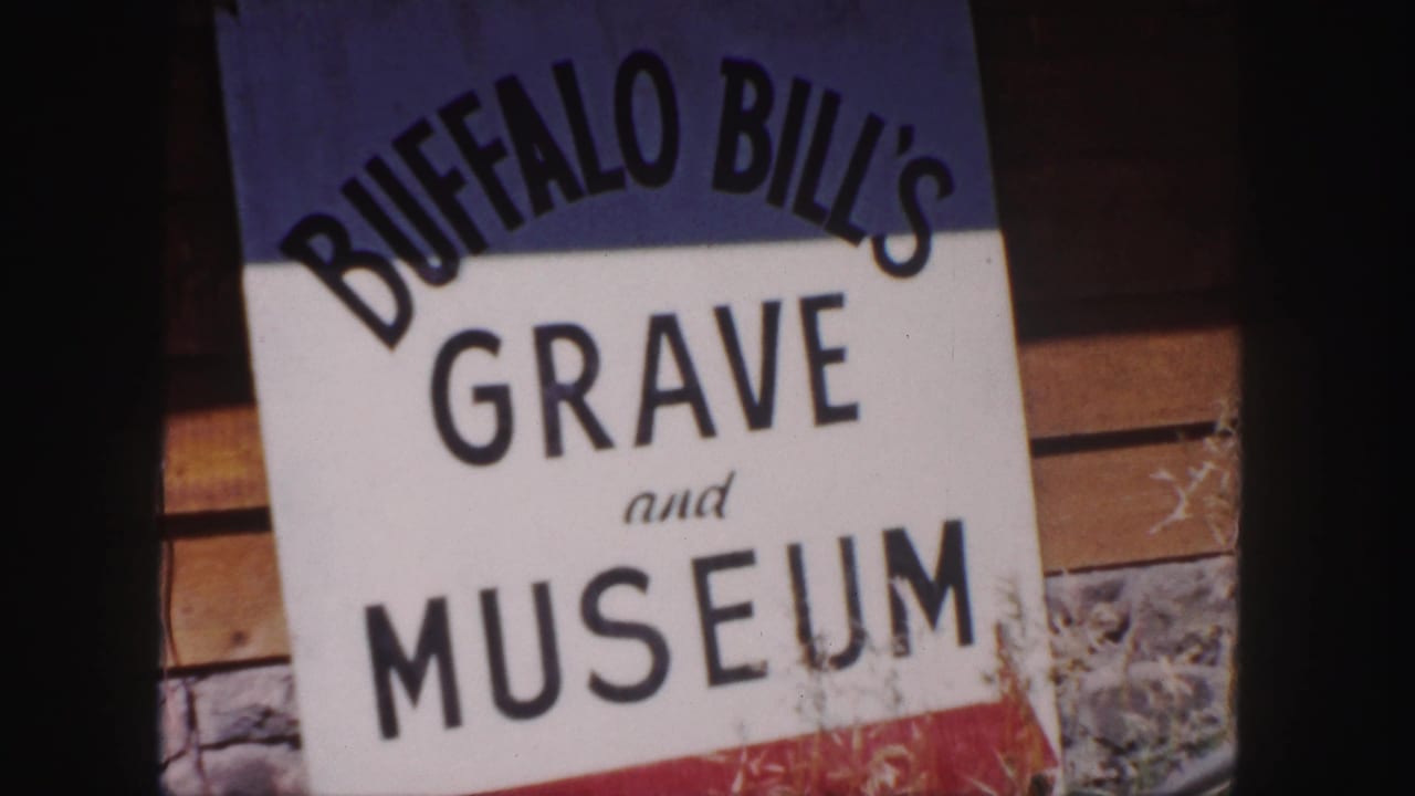 Close view of a Buffalo Bill's Grave and Museum sign beside wood siding and stonework.