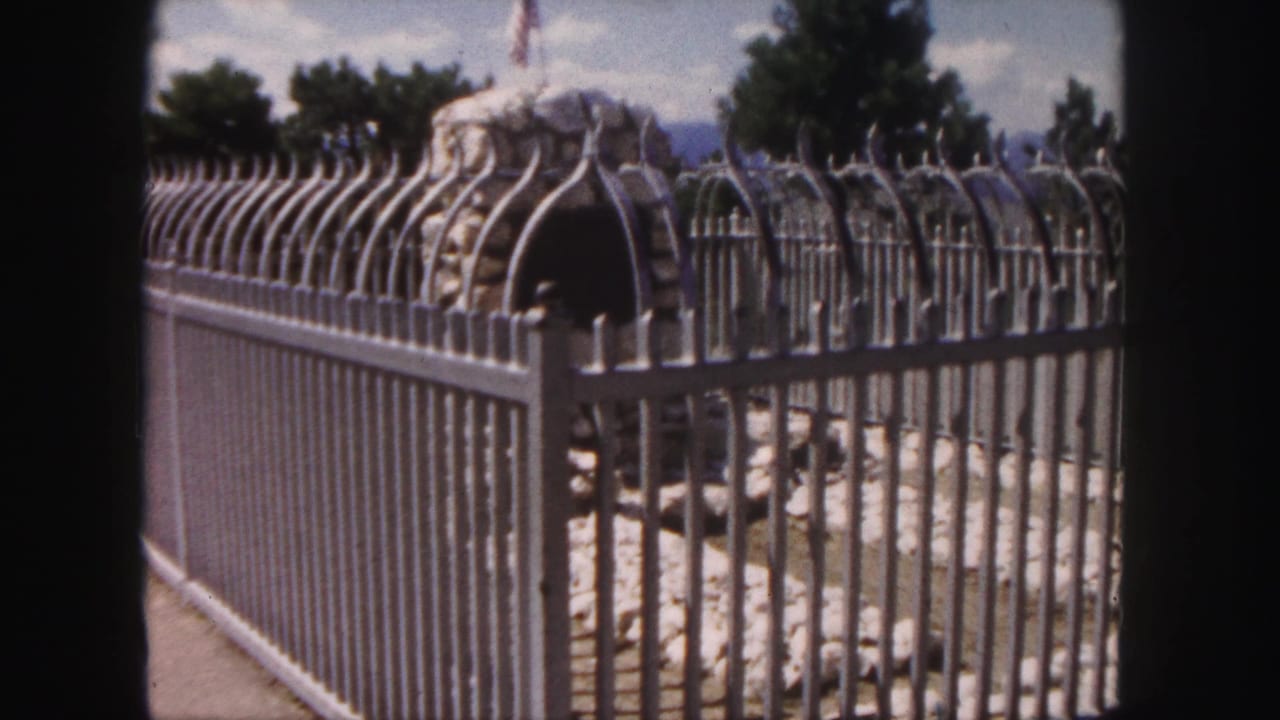 Decorative metal fence in front of a stone structure with an American flag above it.