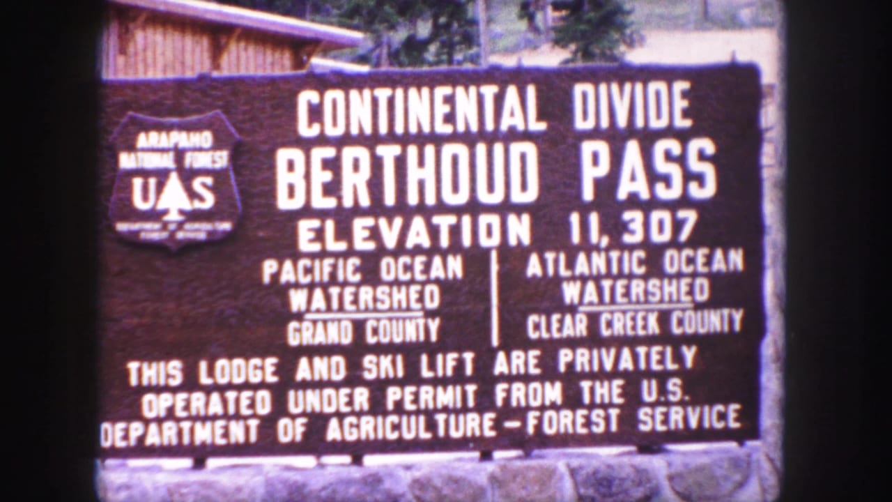 1958 Colorado home-movie frame showing the Berthoud Pass Continental Divide sign at elevation 11,307 feet.