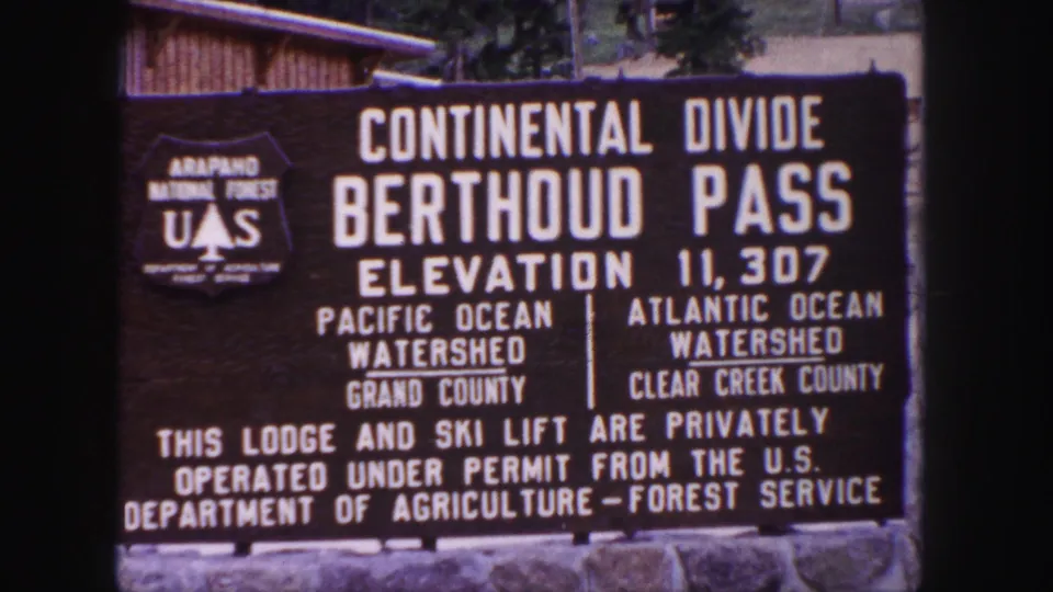 1958 Colorado 8mm frame showing the Berthoud Pass sign and U.S. Forest Service shield at the Continental Divide.
