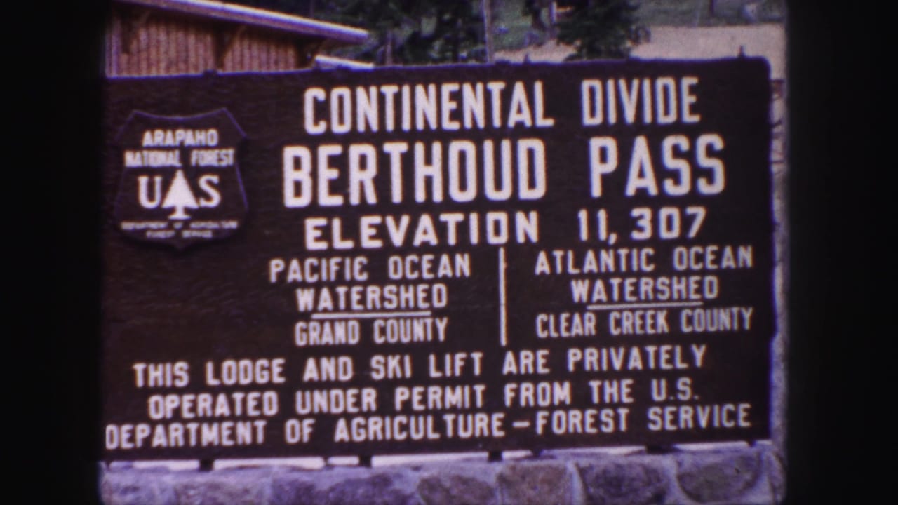 1958 8mm frame of the Berthoud Pass Continental Divide sign showing elevation 11,307 and U.S. Forest Service markings.