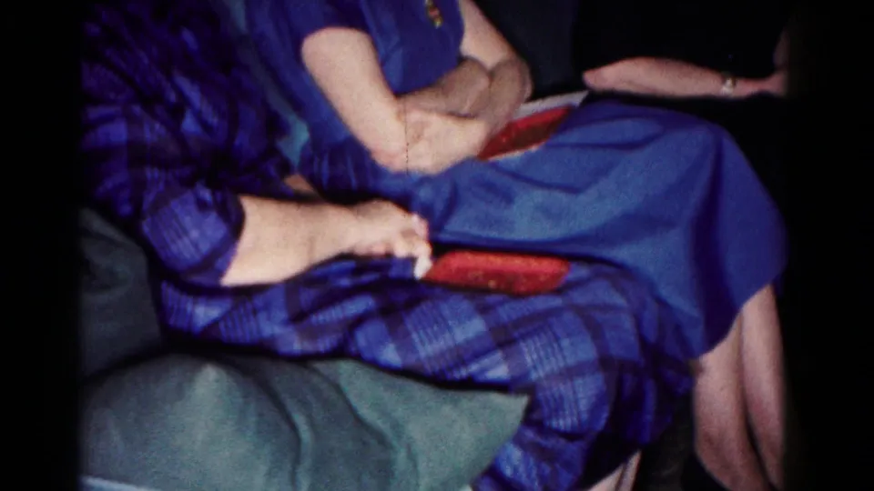 Two women in blue clothing sit on a sofa in the Hagerstown home, with another seated person partly visible at the edge.
