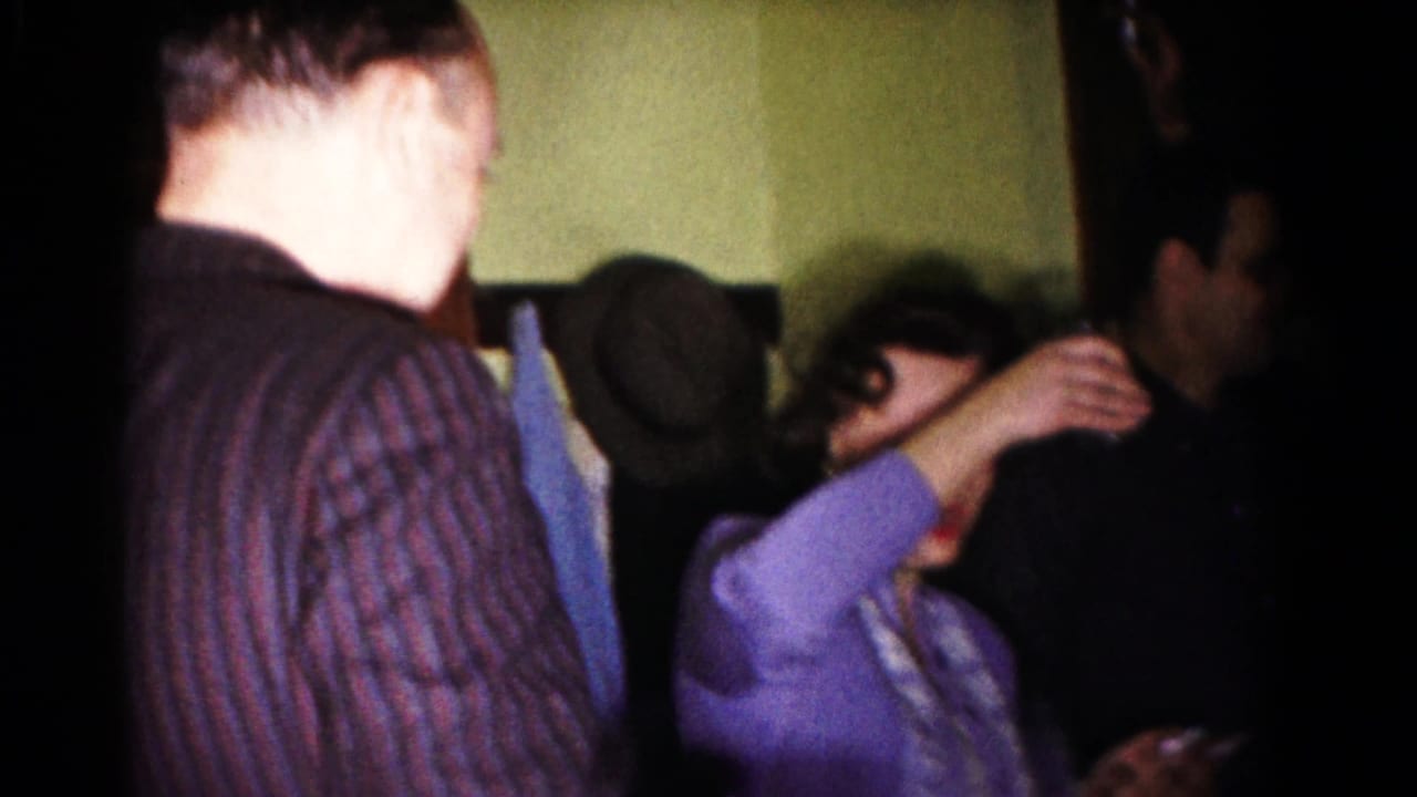Adults stand close together as a woman in purple adjusts her hair.